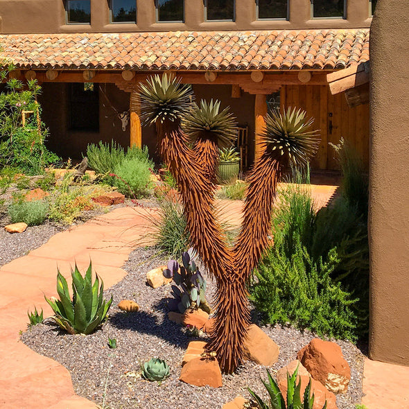 Metal Joshua Tree in yard, next to pathway in landscape bed