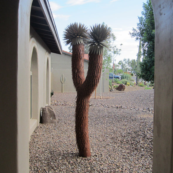 Metal Joshua Tree in landscape bed next to house