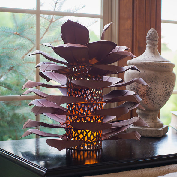 Pine Cone Luminary on end table with vase, next to window