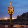 Steel Saguaro Sculpture lit up at night with cityscape in background