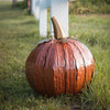 Steel pumpkin luminary in yard, orange squatty