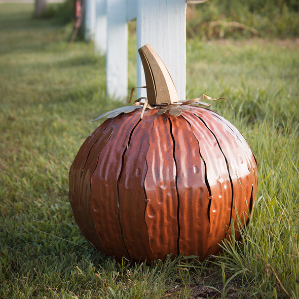 Steel pumpkin luminary in yard, orange squatty